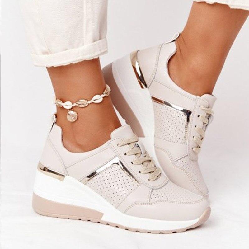 Beige Damen-Sneaker mit Keilabsatz, goldenen Akzenten und Muschel-Fußkettchen. Modische Schuhe, ideal für trendige Freizeitoutfits.