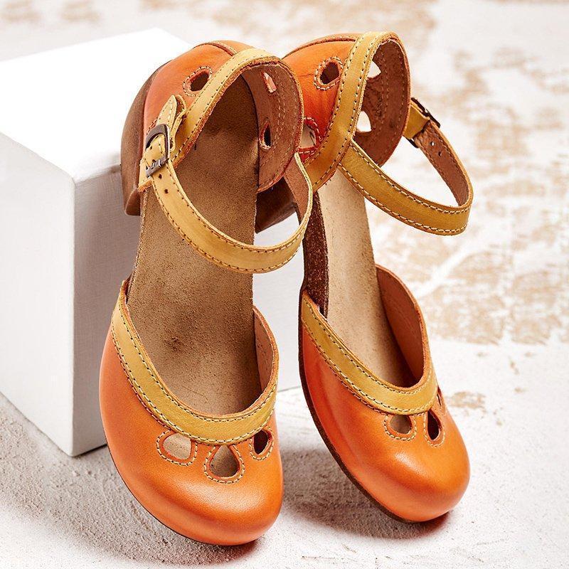 Orange-braune Vintage-Mary-Jane-Schuhe mit Riemen und Lochmuster auf hellem Hintergrund. Retro-Damenschuhe, modisch und bequem.