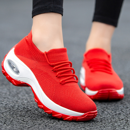 Rote Damen-Sneaker mit weißer Sohle, atmungsaktives Mesh-Obermaterial, ideal für Laufen und Sport, modisches Design auf Asphalt.
