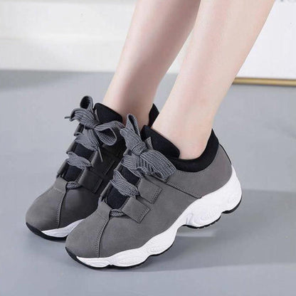 Graue Damen-Sneaker mit dicker weißer Sohle und schwarzen Details, ideal für Sport und Freizeit. Bequeme Turnschuhe mit modischem Design.