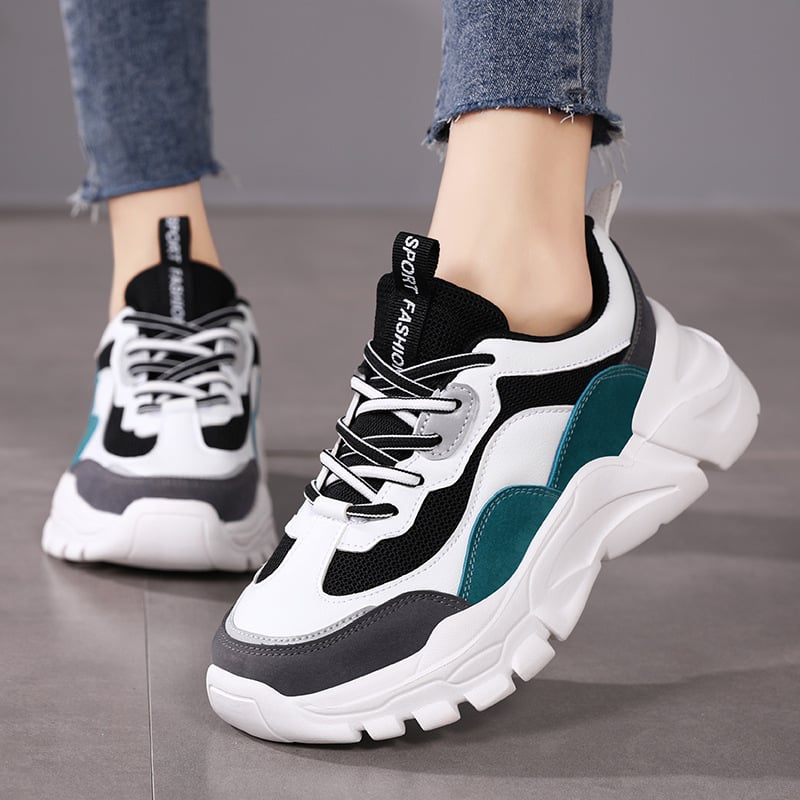 Damen-Sneaker in Schwarz, Weiß und Türkis mit dicker Sohle, getragen mit blauen Jeans. Modische Sportschuhe, ideal für Freizeit und Sport.