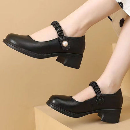 Schwarze Mary Jane Schuhe mit niedrigem Absatz und elastischem Riemen, getragen von einer Person. Elegante Damenschuhe, ideal für formelle Anlässe.