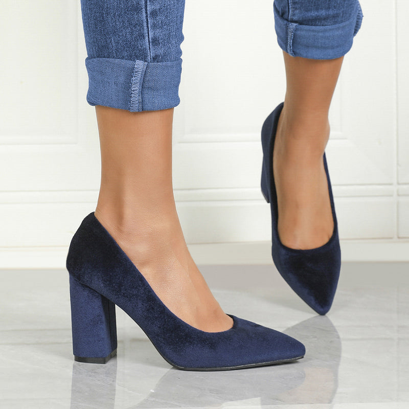 Damenbeine in blauen Samt-High-Heels, kombiniert mit hochgekrempelten Jeans. Elegante Schuhe, modischer Look, stilvolle Damenmode.