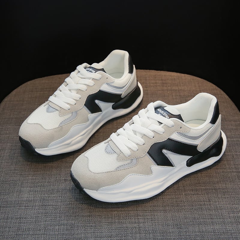 Weiße und graue Sneaker mit schwarzem Detail auf grauem Hintergrund. Modische Sportschuhe, bequeme Turnschuhe, ideal für Freizeit und Sport.