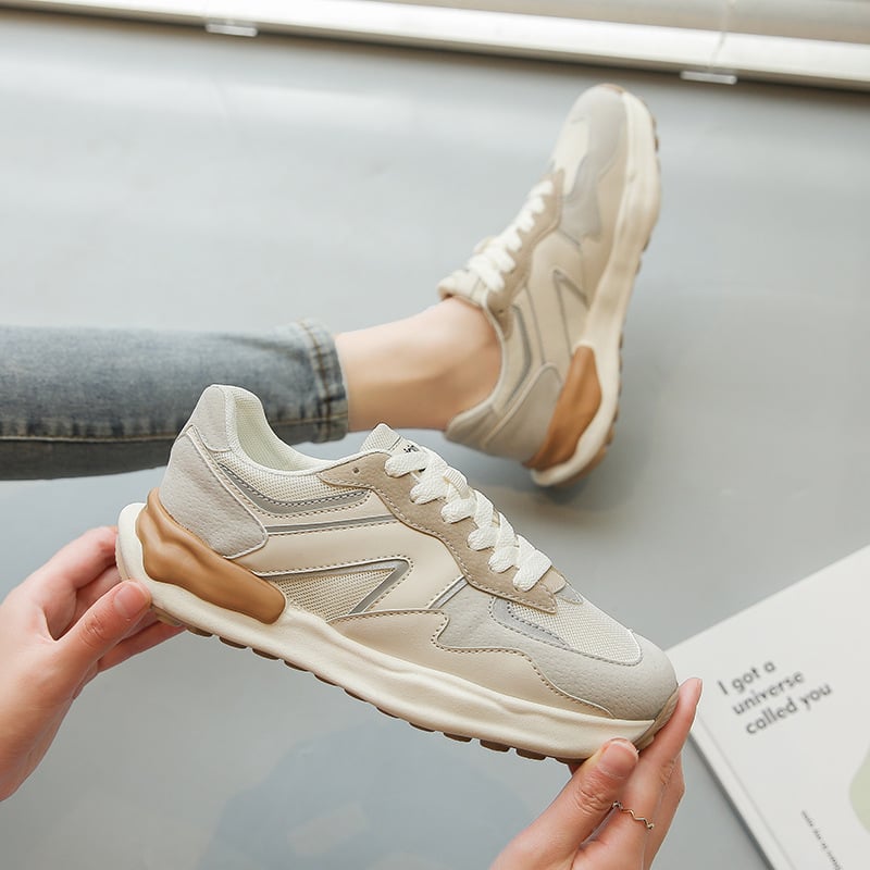 Beige Sneaker mit weißer Sohle und braunen Akzenten, getragen von Person in Jeans. Moderner Sportschuh, ideal für Freizeit und Alltag.