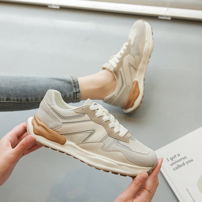 Beige Sneaker mit weißer Sohle und braunen Akzenten, getragen von Person in Jeans. Moderner Sportschuh, ideal für Freizeit und Alltag.