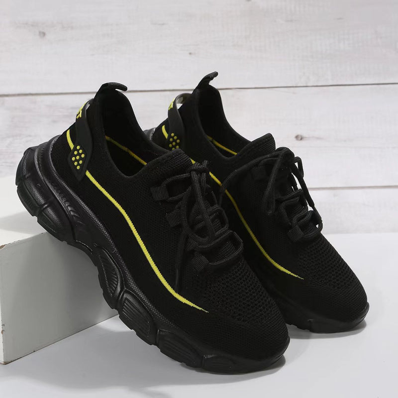 Schwarze Sportschuhe mit gelben Akzenten auf weißem Hintergrund. Atmungsaktives Mesh, robuste Sohle. Ideal für Laufen und Fitness.