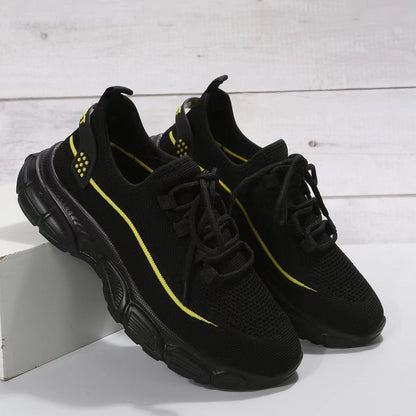 Schwarze Sportschuhe mit gelben Akzenten auf weißem Hintergrund. Atmungsaktives Mesh, robuste Sohle. Ideal für Laufen und Fitness.