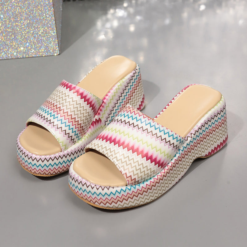 Bunte Plateau-Sandalen mit Zickzackmuster auf grauem Hintergrund. Modische Sommerschuhe, Damenmode, trendige Plateau-Absätze.