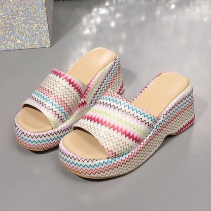 Bunte Plateau-Sandalen mit Zickzackmuster auf grauem Hintergrund. Modische Sommerschuhe, Damenmode, trendige Plateau-Absätze.