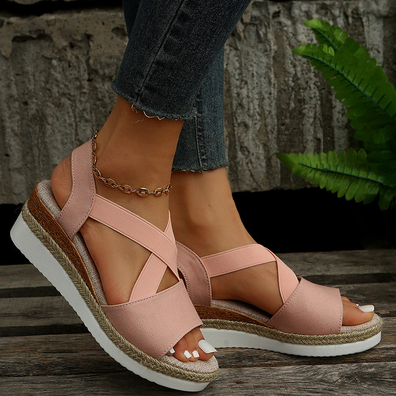 Damen Sandalen in Rosa mit Keilabsatz und Kreuzriemen, getragen mit Jeans. Bequeme Sommerschuhe, modisch und ideal für Freizeitoutfits.