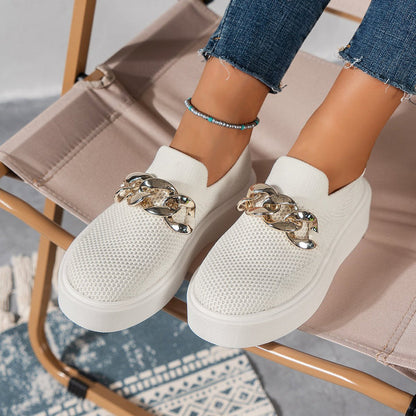 Weiße Damen-Sneaker mit goldener Kette, lässig und modisch, auf einem Stuhl. Perfekt für trendige Freizeitoutfits und bequemen Alltagsstil.