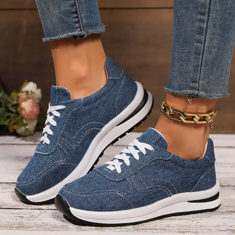 Damen Sneaker aus blauem Denim mit weißer Sohle und Schnürsenkeln, getragen mit Jeans. Modische Freizeitschuhe, ideal für den Alltag.