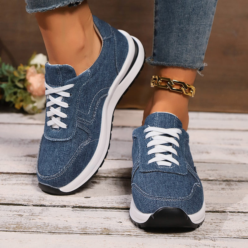 Damen Sneaker aus Jeansstoff mit weißer Sohle und Schnürsenkeln, getragen mit Jeans und goldener Kette. Modische Freizeitschuhe für Damen.