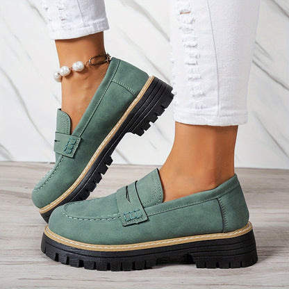 Grüne Damen-Loafer mit dicker Sohle, getragen mit weißen Jeans. Modische Schuhe, ideal für Herbsttrends und lässige Outfits.