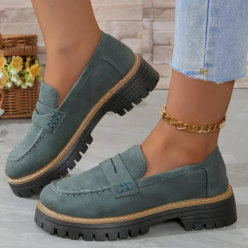 Damen Loafer in Grün mit dicker Sohle, kombiniert mit Jeans und goldener Fußkette. Modische Schuhe für Herbst, bequem und stilvoll.
