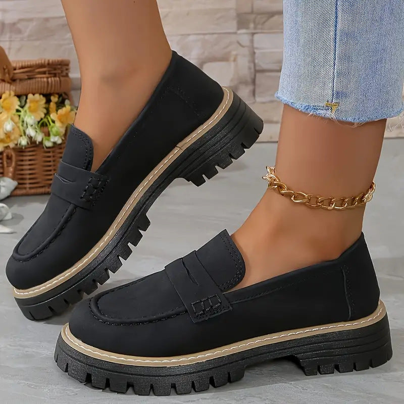 Schwarze Damen-Loafer mit dicker Sohle, getragen mit hellblauen Jeans. Modische Schuhe, ideal für Herbsttrends und lässige Outfits.