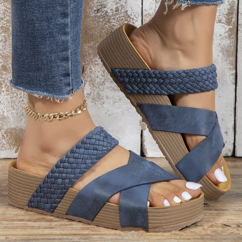 Damenfüße in blauen, geflochtenen Sandalen mit Keilabsatz und Jeans. Modische Sommerschuhe, bequeme Sandalen, trendige Fußbekleidung.