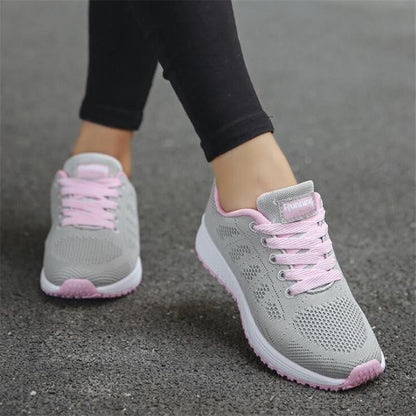 Graue Damen-Laufschuhe mit rosa Schnürsenkeln auf Asphalt. Bequeme Sportschuhe für Fitness und Jogging. Ideal für Outdoor-Aktivitäten.