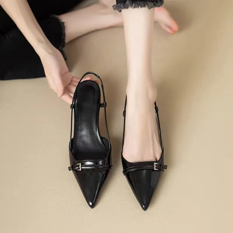 Schwarze spitze Slingback-Ballerinas mit Schnalle, getragen von einer Person auf beigem Hintergrund. Elegante Damen-Sommerschuhe, modisch und stilvoll.