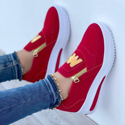 Rote Damen-Sneaker mit goldenen Reißverschlüssen und weißer Sohle, getragen mit blauen Jeans. Modische Freizeitschuhe, trendiger Look.