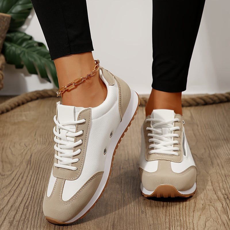 Damen-Sneaker in Weiß und Beige auf Holzboden, modisch und bequem, mit goldener Fußkette. Ideal für Freizeit und Sport.