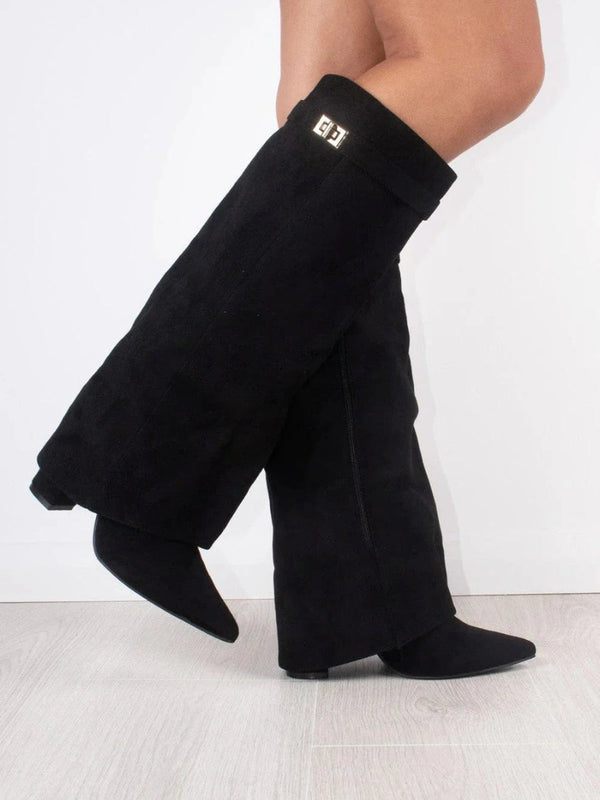Schwarze Overknee-Stiefel aus Wildleder mit flachem Absatz, seitlichem Logo-Detail, getragen auf hellem Holzboden. Modische Damenstiefel.