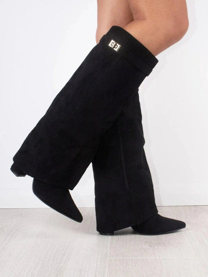 Schwarze Overknee-Stiefel aus Wildleder mit flachem Absatz, seitlichem Logo-Detail, getragen auf hellem Holzboden. Modische Damenstiefel.