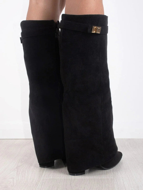 Schwarze, kniehohe Stiefel aus Wildleder mit goldener Schnalle, seitlich fotografiert auf hellem Holzboden. Modische Damenstiefel, elegant und zeitlos.