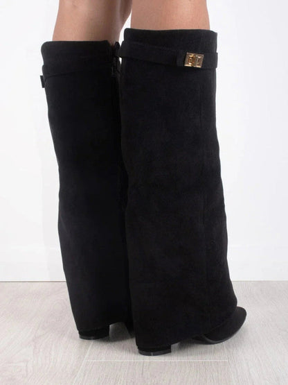 Schwarze, kniehohe Stiefel aus Wildleder mit goldener Schnalle, seitlich fotografiert auf hellem Holzboden. Modische Damenstiefel, elegant und zeitlos.
