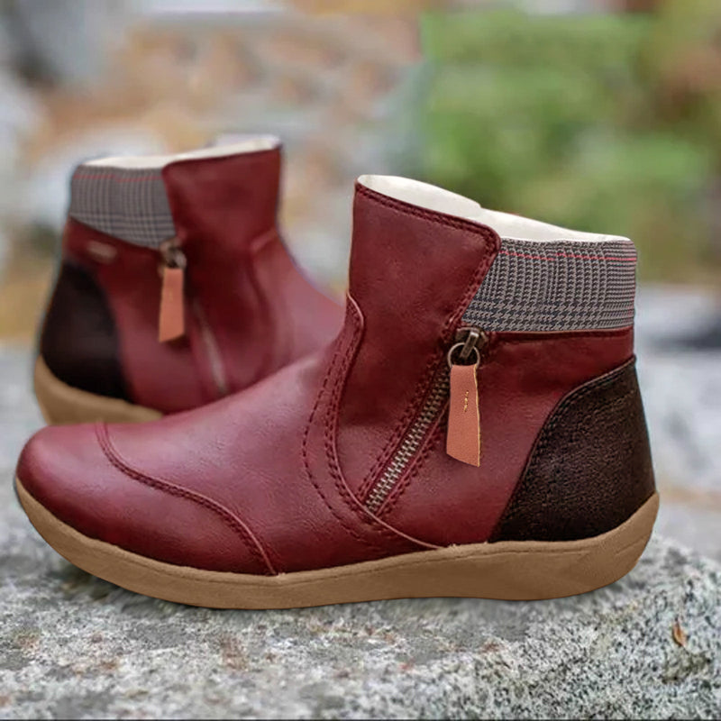 Rote Damenstiefeletten mit Reißverschluss, brauner Ferse und beigem Gummisohle, auf Stein im Freien. Modische Herbstschuhe, bequem und stilvoll.