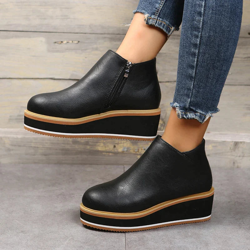 Schwarze Plateau-Stiefeletten mit Reißverschluss, kombiniert mit blauen Jeans. Modische Damen-Schuhe, ideal für Herbst-Outfits und urbanen Stil.