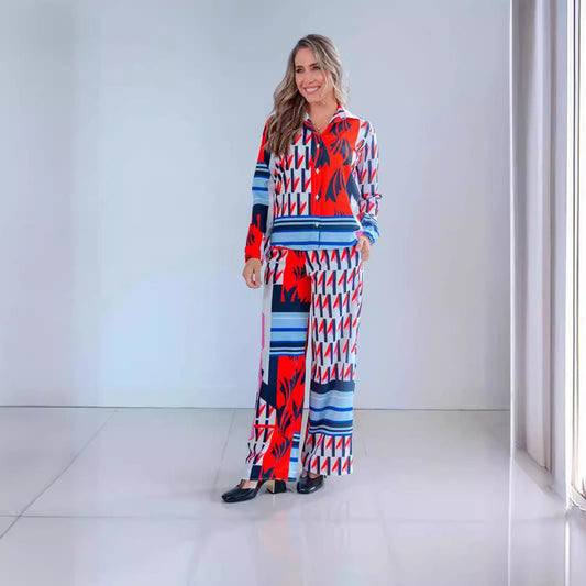 Frau in buntem, geometrisch gemustertem Anzug, lächelt in modernem, minimalistischem Raum. Modetrend, Damenbekleidung, stilvolles Outfit.