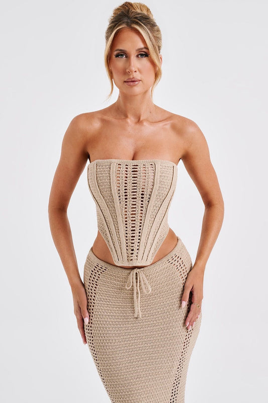 Frau in beige gestricktem, schulterfreiem Kleid mit Korsett-Design, modisch elegant, Studioaufnahme, Sommermode, trendiges Outfit.