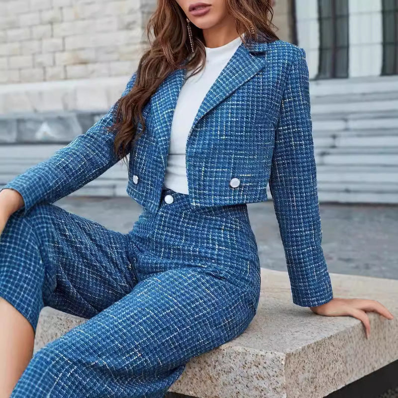 Frau in blauem Tweed-Anzug mit weißem T-Shirt, sitzt auf einer Steinbank. Modetrend, eleganter Damenanzug, stilvolle Freizeitkleidung.