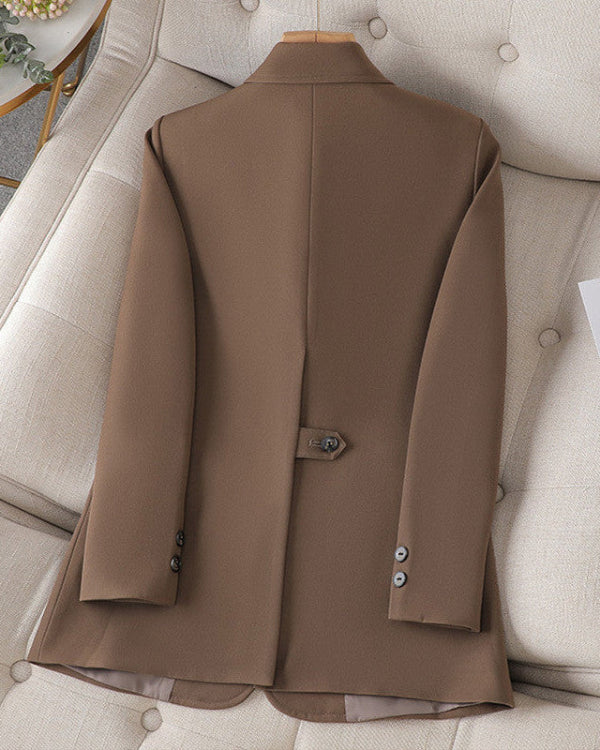 Brauner Herrenblazer aus Wolle, elegant auf beigem Sofa drapiert, mit Knöpfen an den Ärmeln und Rückenschlaufe. Perfekt für formelle Anlässe.