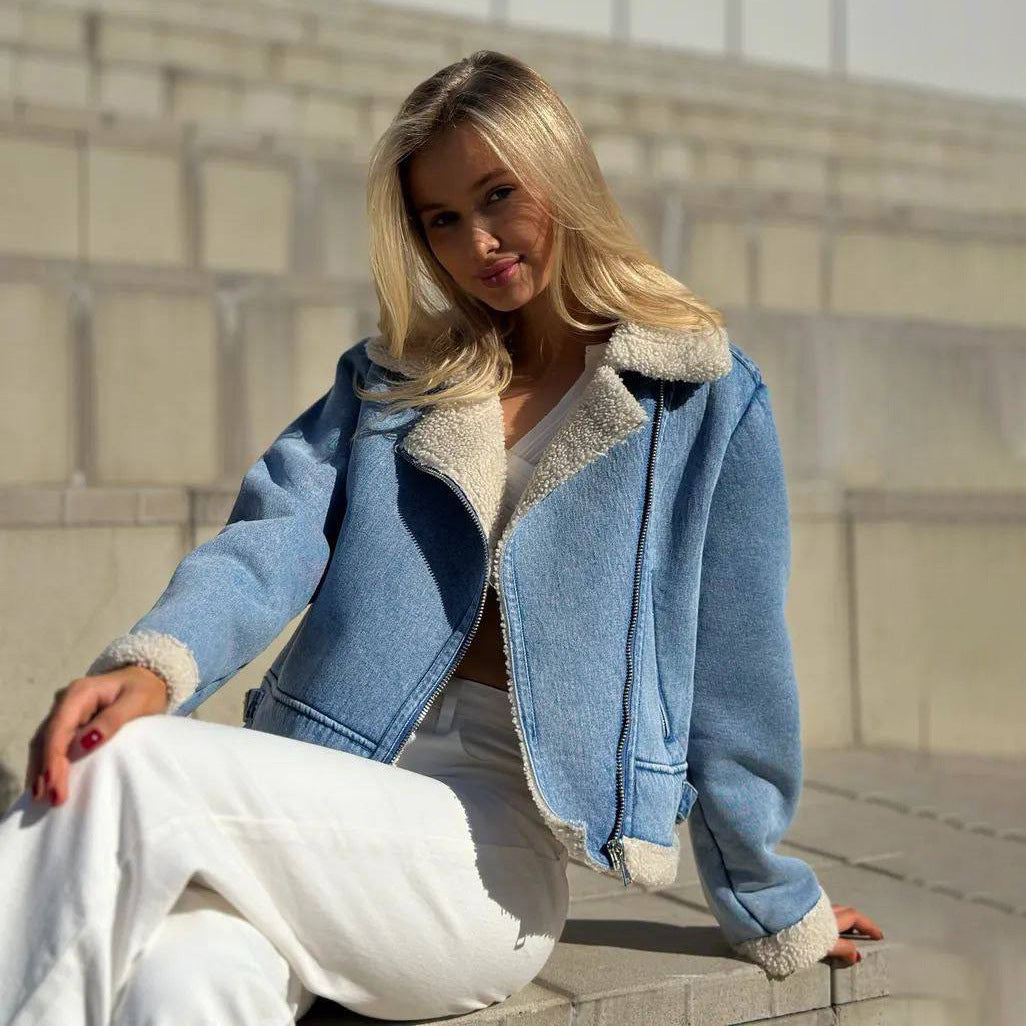 Blonde Frau in blauer Jeansjacke mit Fellkragen sitzt auf Treppe. Modetrend, Herbstmode, lässiger Stil, Outdoor-Fotoshooting.
