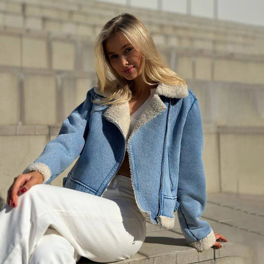 Blonde Frau in blauer Jeansjacke mit Fellkragen sitzt auf Treppe. Modetrend, Herbstmode, lässiger Stil, Outdoor-Fotoshooting.