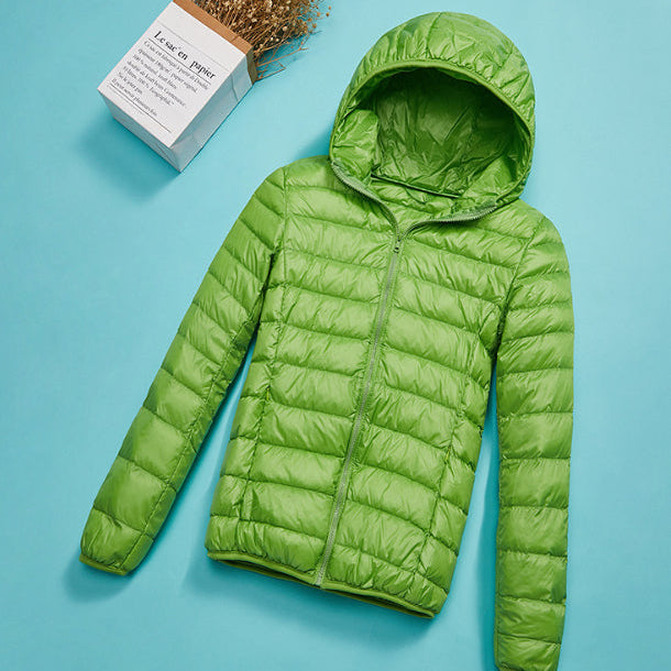 Grüne Daunenjacke mit Kapuze auf blauem Hintergrund, modische Winterbekleidung, leicht und warm, ideal für Outdoor-Aktivitäten.