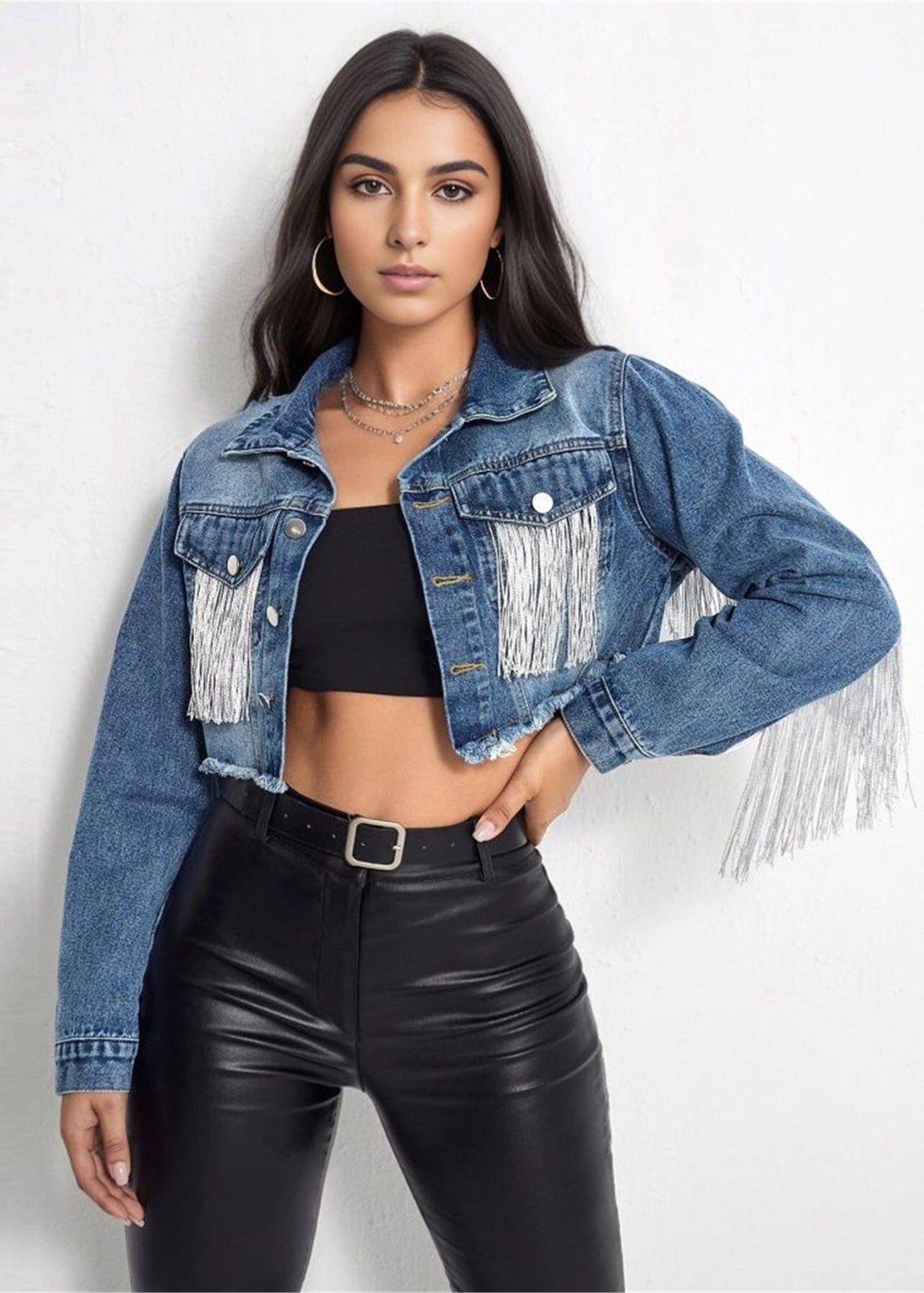 Frau in modischer Jeansjacke mit Fransen, schwarzem Top und Lederhose. Trendige Damenmode, Streetstyle, Denim-Look, lässiger Chic.