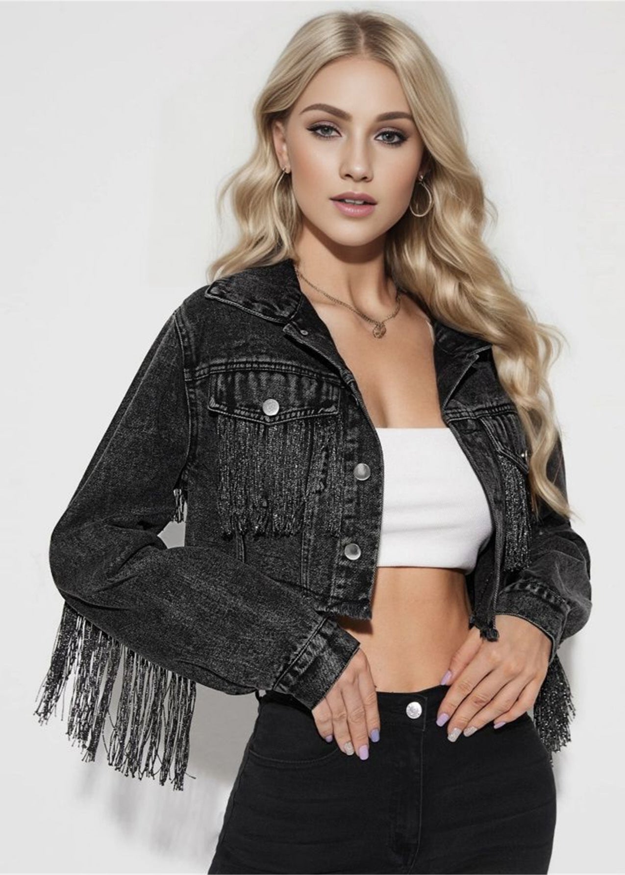 Blonde Frau in schwarzer Fransen-Jeansjacke, weißem Top und schwarzer Hose. Modetrend, Damenbekleidung, stilvolle Freizeitmode.