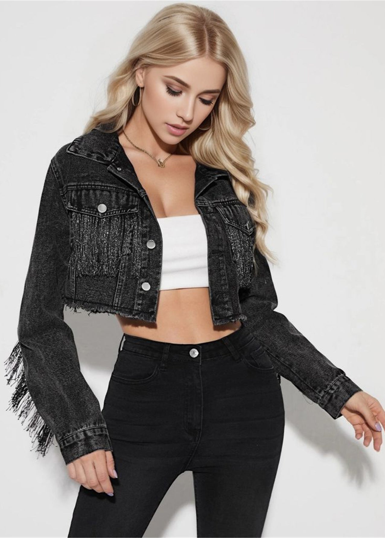 Frau in schwarzer Jeansjacke mit Fransen, weißem Top und schwarzer Hose. Modetrend, Damenbekleidung, stilvolle Freizeitmode.