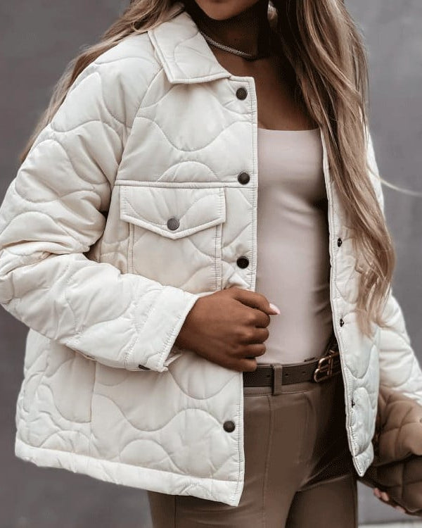 Dame in beiger, gesteppter Jacke mit Knopfleiste und Brusttasche, kombiniert mit beigem Top und Hose. Modetrend Herbst, stilvolle Damenbekleidung.