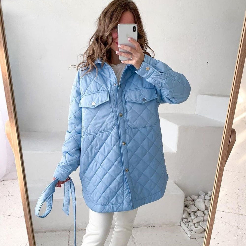 Frau in hellblauer Steppjacke macht Selfie. Modetrend, Winterjacke, Damenmode, stilvoll, modern, Freizeitlook, Innenraum, Smartphone.