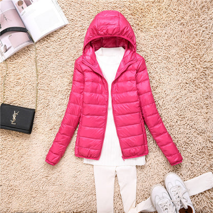 Damen Winterjacke in Pink mit Kapuze, auf Teppich liegend. Kombiniert mit weißem Pullover und Hose. Modetrend, warme Kleidung, stilvoll.