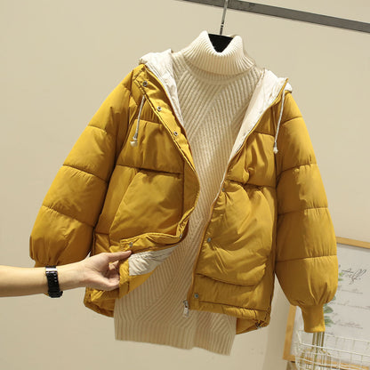 Gelbe Daunenjacke mit Kapuze über cremefarbenem Rollkragenpullover, modische Winterbekleidung, warme Outdoor-Jacke, stilvoll und funktional.
