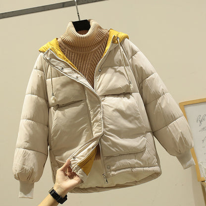 Beige Daunenjacke mit gelbem Innenfutter und Kapuze, über einem beigen Rollkragenpullover. Wintermode, warme Oberbekleidung, stilvoll und gemütlich.