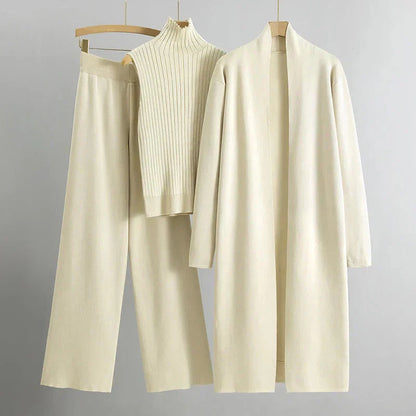 Beige Damen Strickset: Langer Cardigan, ärmelloser Rollkragenpullover und weite Hose. Elegante, minimalistische Mode für Herbst und Winter.