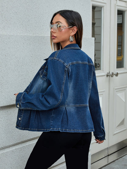 Frau in blauer Jeansjacke und Sonnenbrille, steht vor weißer Tür. Modetrend, Streetstyle, lässiger Look, Damenmode, urbaner Stil.