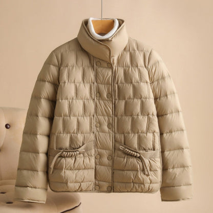 Beige Daunenjacke mit Stehkragen, gestepptem Design und Knopfleiste, hängend vor neutralem Hintergrund. Wintermode, warme Oberbekleidung.